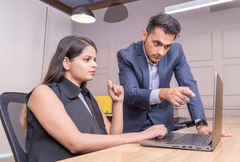boss explaining work to employee on laptop